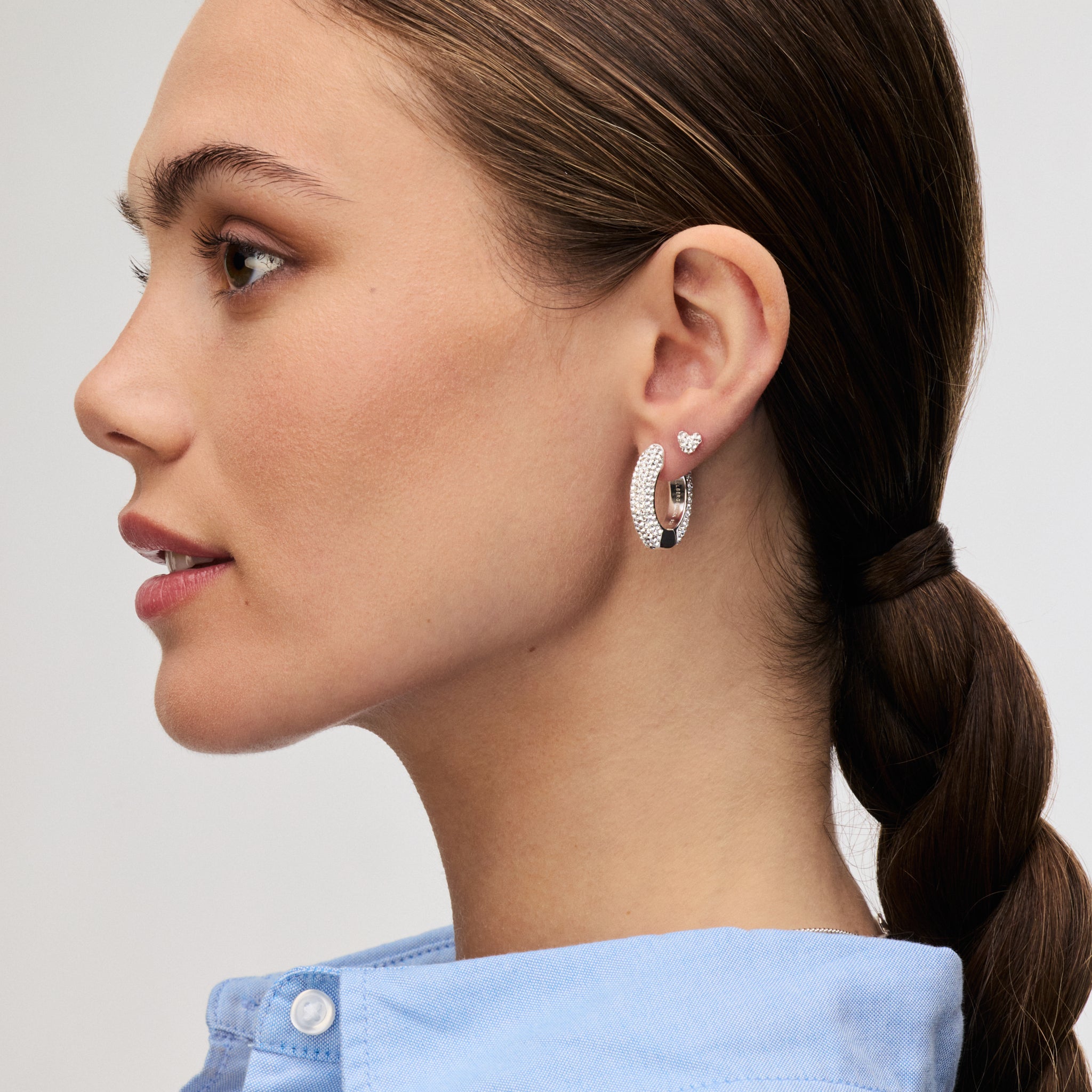 White Medium Sparkle Hoop Earrings and Silver Mini Heart Stud Earrings on model